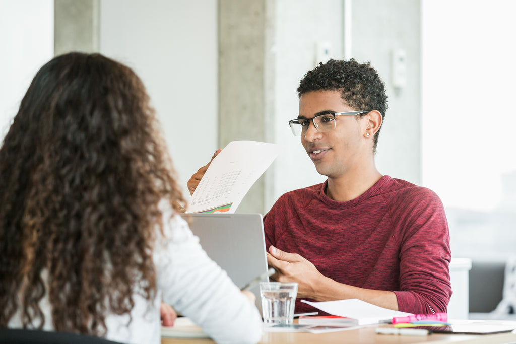 young-man-in-meeting-going-over-reports